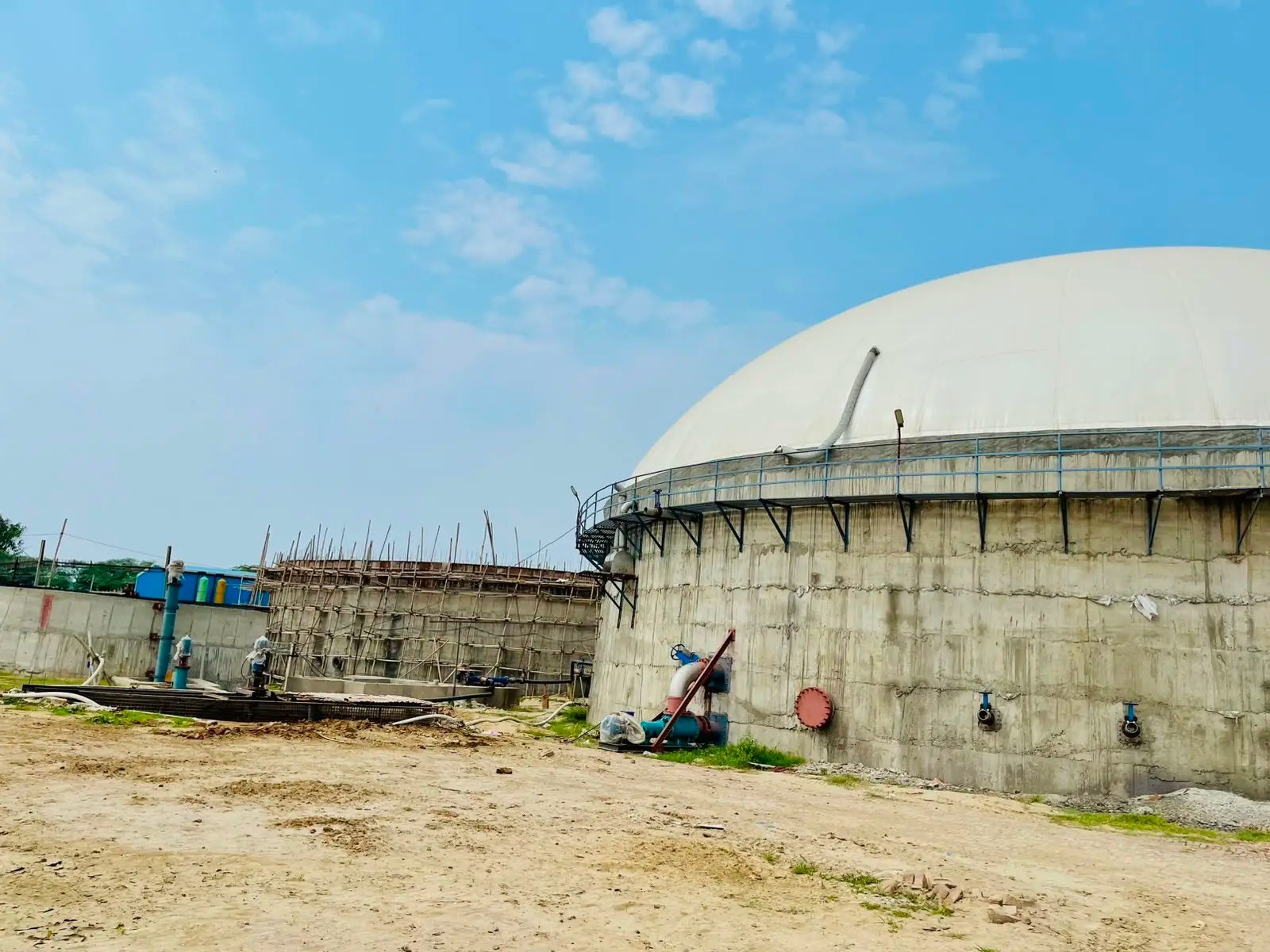 White membrane gas holder dome on a concrete digester tank with a perimeter walkway and valves